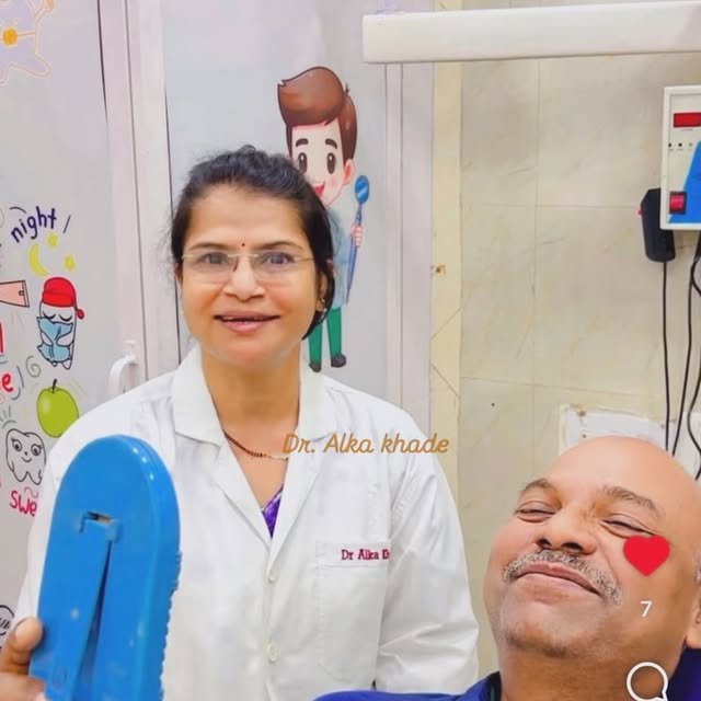 Dr. Alka with a happy patient holding a dental mirror